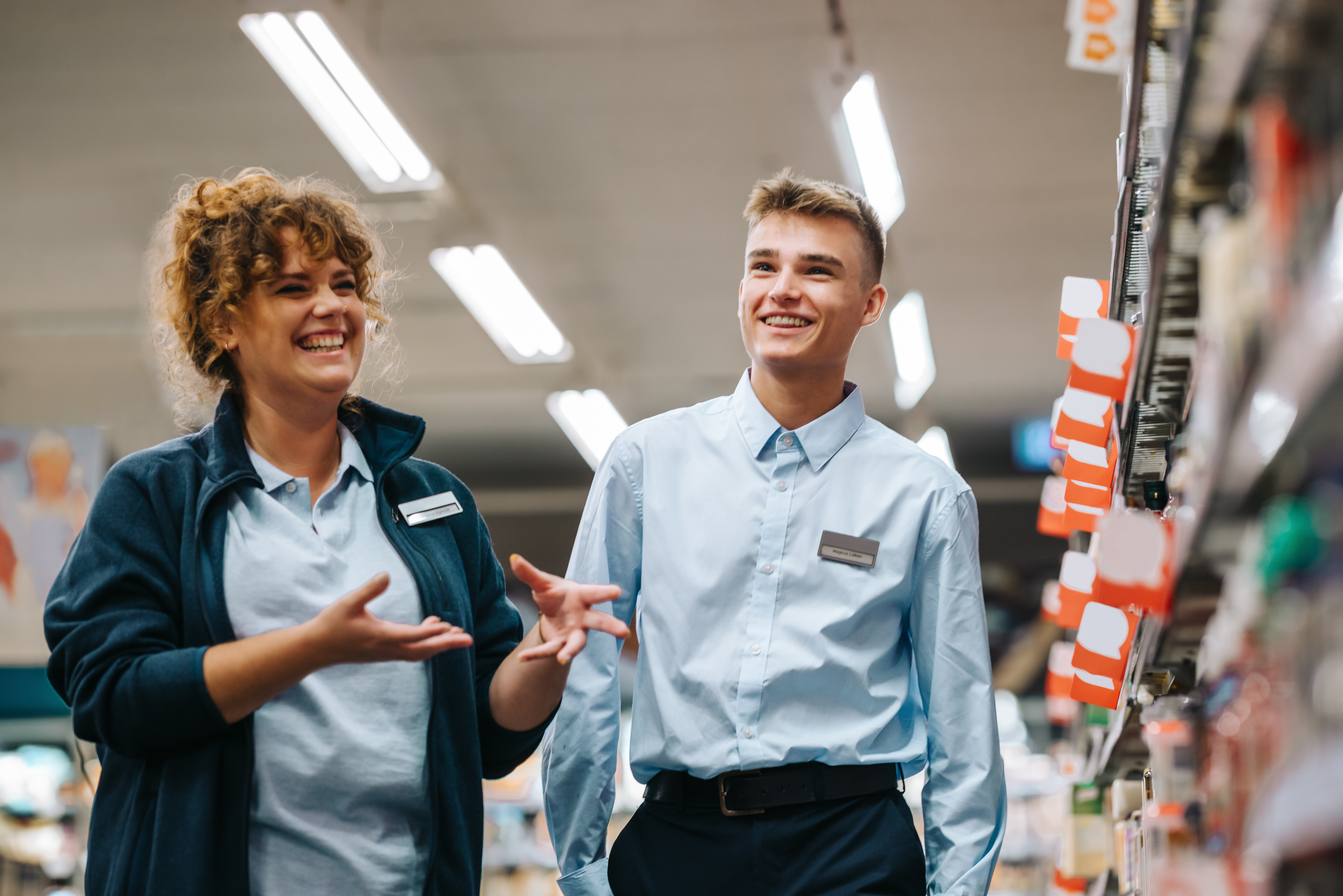 Smiling retail manager and employee in front of a shelf